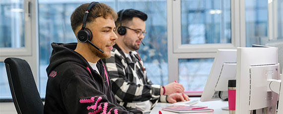 Zwei Magenta Servicmitarbeiter vor dem Bildschirm Zwei Magenta Servicmitarbeiter vor dem Bildschirm