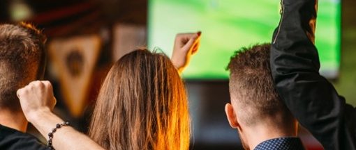 Gruppe jubelt beim Mitfiebern vor großem Bildschirm – gemeinsames Streaming von Sportevents