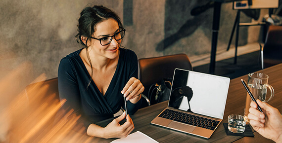 Eine Frau arbeitet gemeinsam mit einem Kollegen, zwischen ihnen steht ein Laptop am Tisch