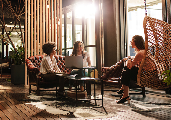 Drei Frauen sitzen an einem Tisch und führen eine Besprechung