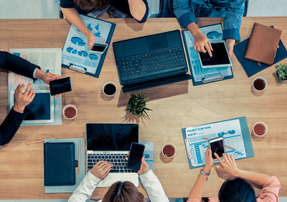 Hardware Managed Service Team bei einer Projektbesprechung am Tisch, alle nutzen Laptop und Smartphone