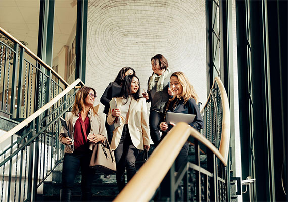 Fünf Business Frauen verlassen gemeinsam ein Gebäude, Networking und Female Leadership im Fokus