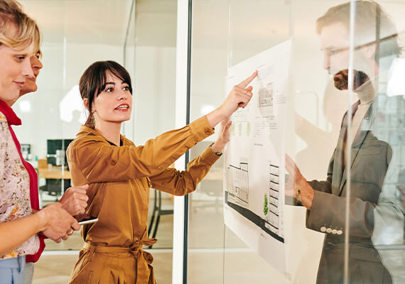 Team bespricht Projektpläne an Glaswand im modernen Büro – Präsentation mit visuellen Charts