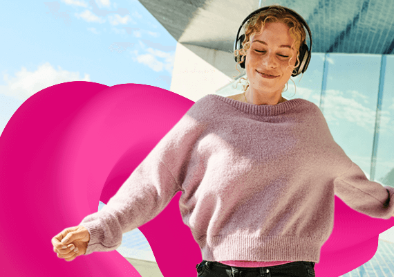 Frau tanzt mit Kopfhörern vor urbanem Hintergrund, Musikgenuss mit markantem Magenta Design