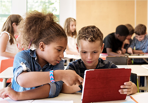 Zwei Grundschulkinder arbeiten gemeinsam am Tablet, digitales und kollaboratives Lernen im Unterricht