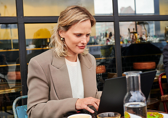 SecurePIM Office Businessfrau arbeitet an Laptop im Café, mobiles Arbeiten in entspannter Atmosphäre