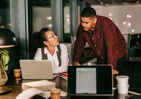 Ein Mann und eine Frau arbeiten gemeinsam an einem Laptop in einem modernen Büro. Ein Mann und eine Frau arbeiten gemeinsam an einem Laptop in einem modernen Büro.