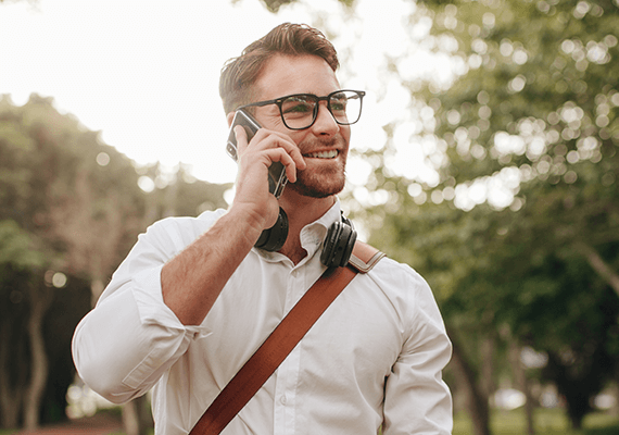 Ein Mann mit Brille geht spazieren und telefoniert dabei