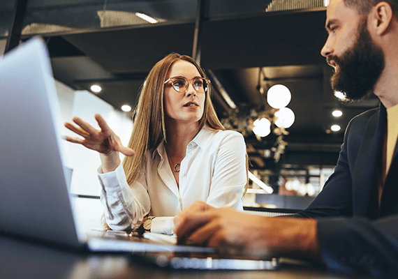 Zwei Personen sitzen vor einem Laptop in einer Besprechung