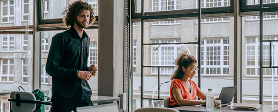 Zwei Personen in einem modernen Büro Zwei Personen arbeiten an ihren Schreibtischen in einem modernen Büro