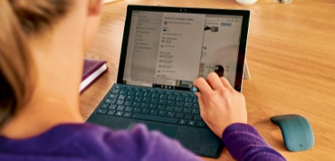 Frau arbeitet an einem Tablet mit Tastatur und Maus am Schreibtisch