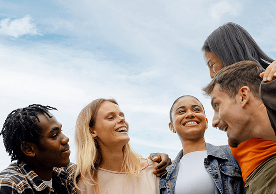 Mehrere Personen lachen entspannt vor blauem Himmel.