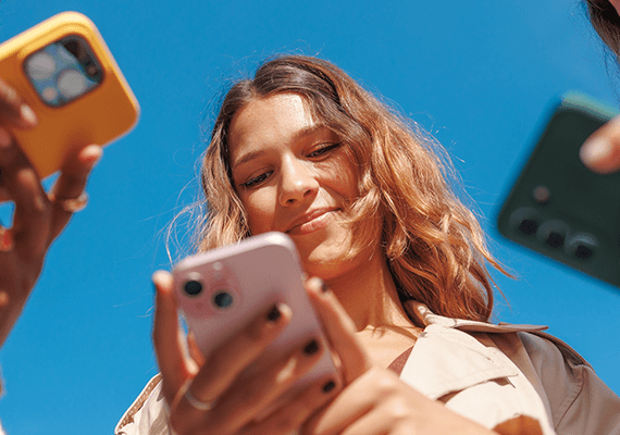 Mehrere Personen sind von unten zu sehen und halten ihre Handy über die Kamera, eine blonde Frau lächelt während sie auf ihren Bildschirm schaut.