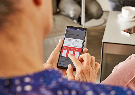 Eine Person hält ein Handy und tippt mit dem Finger auf ein Element am Bildschirm