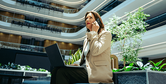 Eine Frau sitzt in einem Innenhof und telefoniert