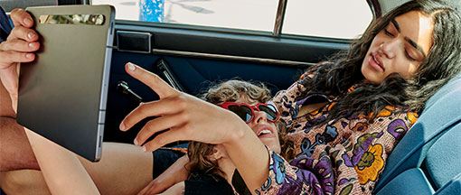 Junges Paar mit Tablet auf Rücksitz im Auto Junges Paar mit Tablet auf Rücksitz im Auto