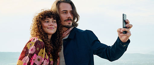 Paar macht gemeinsam ein Selfie am Strand mit Meer im Hintergrund