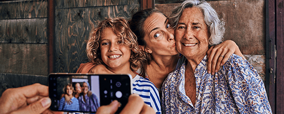 Ein Kind, ein junge und eine ältere Frau werden mit einem Smartphone fotografiert Ein Kind, ein junge und eine ältere Frau werden mit einem Smartphone fotografiert