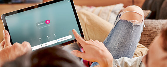 Zwei Personen liegen auf der Couch und halten ein Tablet in der Hand