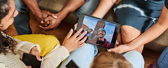 Eine Gruppe von Personen sitzt am Boden und betrachtet ein Tablet.