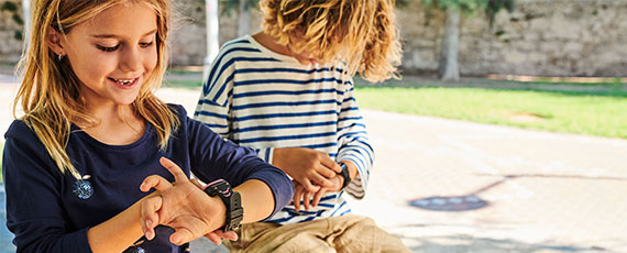 Zwei Kinder schauen jeweils auf ihre Kidswatches Zwei Kinder schauen jeweils auf ihre Kidswatches