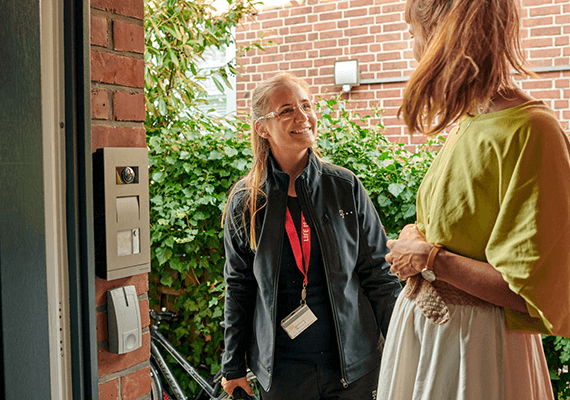 Installation mit Übergabe Technikerin im Gespräch mit Kundin an der Haustür – kompetenter Vor-Ort-Service für Internet und Telekommunikation.