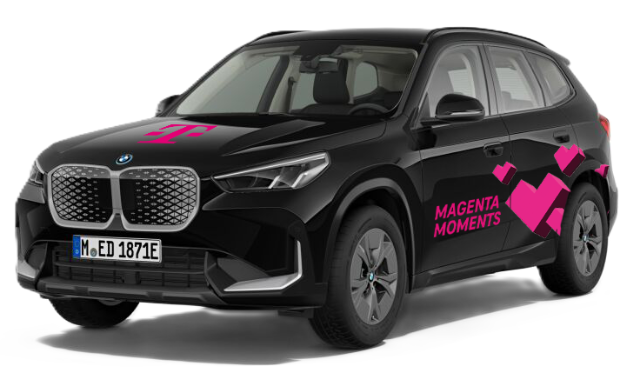 Schwarzer BMW SUV mit auffälligen magentafarbenen Grafiken und Telekom-Logo auf der Motorhaube. Auf der Fahrerseite steht ‚MAGENTA MOMENTS‘ in pinker Schrift, daneben mehrere stilisierte pinke Quadrate. Fahrzeug auf weißem Hintergrund.