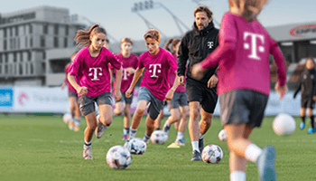 Fussballcamp Mehrere Jugendliche trainieren in Magenta farbenen Trikots am Fußballplatz