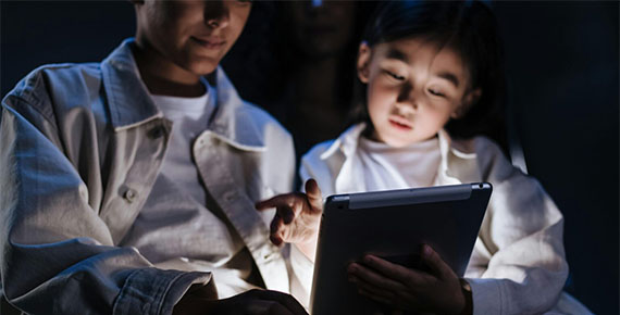 Kind und Erwachsener sehen sich Inhalte am Tablet an