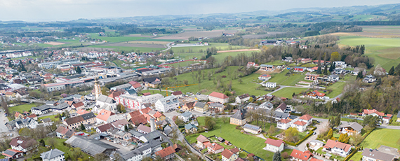 Andorf Luftaufnahme von Andorf mit Kirche im Zentrum, umgeben von Wohnhäusern, Feldern und sanften Hügeln.