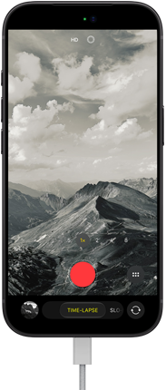 iPhone 18 Pro, Vorderseite, das Display zeigt eine Berglandschaft, mit der Kamera Modus Überlagerung im Zeitraffer Modus, mit dem Netzkabel am Ladeanschluss